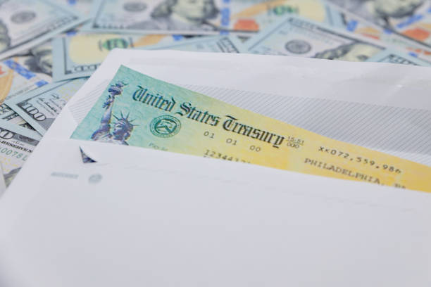 istock Stack of 100 dollar bills with coronavirus stimulus payment check to show the virus payment to Americans. Concept IRS tax refund or coronavirus stimulus payments. Global pandemic Covid 19 lock down 1231646936