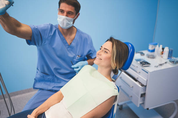 istock Dentist examining a patient's teeth using dental equipment in dentistry office. Stomatology and health concept. Young handsome male doctor in disposable medical facial mask, smiling happy woman. 1231663309