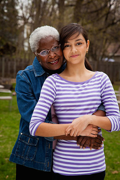 senior woman hugging granddaughter , portrait - generation gap multi generation family vertical holding hands photos et images de collection