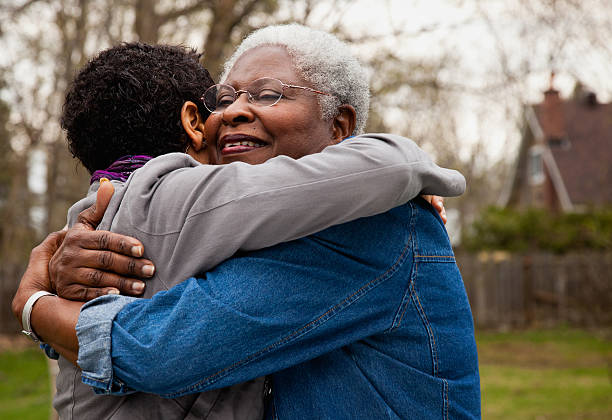 african american senior hugging her daughter - umarmen stock-fotos und bilder