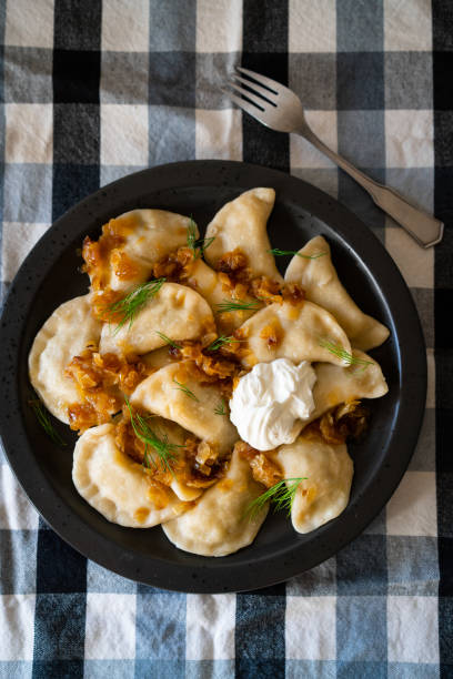 Homemade pierogi with fried onion and sour cream Homemade potato pierogi with fried onion, dill and sour cream pierogi stock pictures, royalty-free photos & images