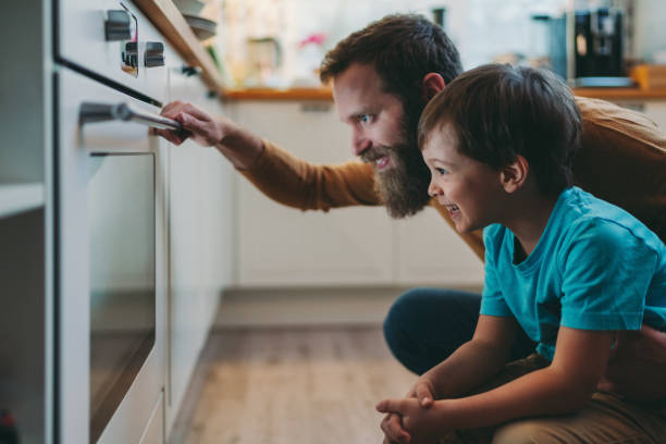 vater und sohn kochen abendessen zu hause - looks back stock-fotos und bilder