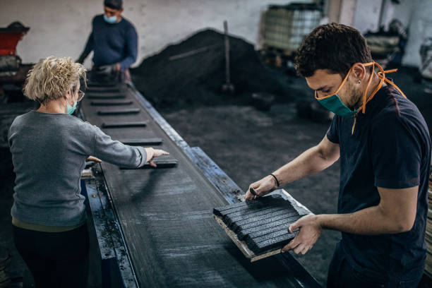 istock Manual workers working on coal for hookah production line in factory 1231724835