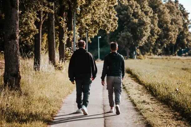 Photo of Friends Walking Together Outdoors on Footpath