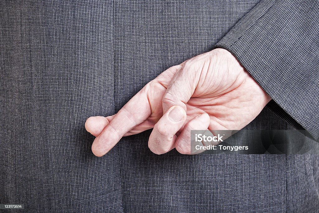 Man in a suit with his fingers crossed behind his back A conceptial image of a business man with his fingers crossed behind his back. Fingers Crossed Stock Photo