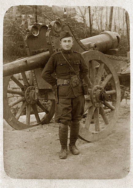 Soldier in Uniform with Cannon Soldier from WWI stands in uniform in front of cannon. sepia toned photos stock pictures, royalty-free photos & images