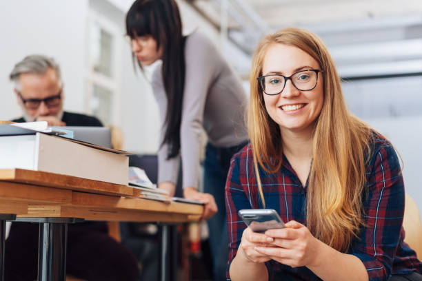 istock Young woman in office on phone smiling at camera 1231793646