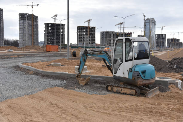istock Mini excavator digg trench to lay cables concrete curbs and paving slabs at construction site. Backhoe on earthwork roadworks 1231798315