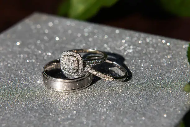 Wedding rings. Inlaid with diamonds. On a shiny gray surface.