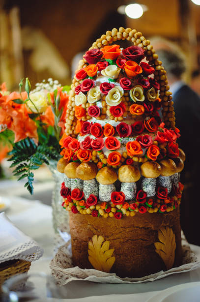 Delicious sweet wedding loaf, decorated with white and red flowers from the mastic. Wedding Bread. Vertical photo