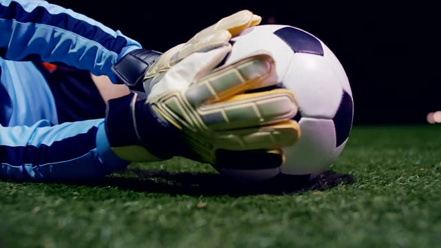 Football game. Soccer action. Goalkeeper jumping for the ball and saving, 4k slow motion