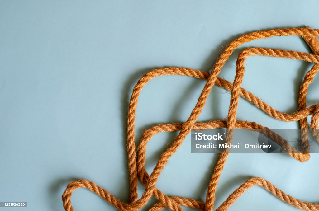 Thin jute rope on a light blue background. Thin jute rope on a light blue background. The natural rope is randomly laid out on the table. Sea travel, beach vacation, fishing. Multitask background for design tasks. Place for text. Abstract Stock Photo