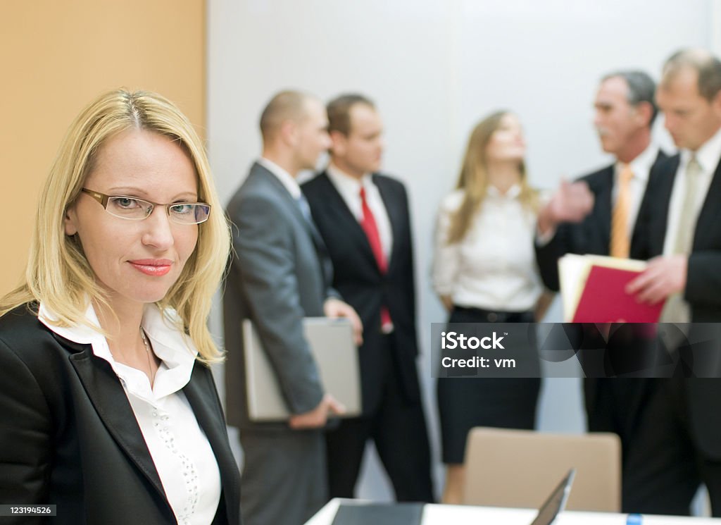 Felice donna d'affari con il suo team in background - Foto stock royalty-free di Adulto