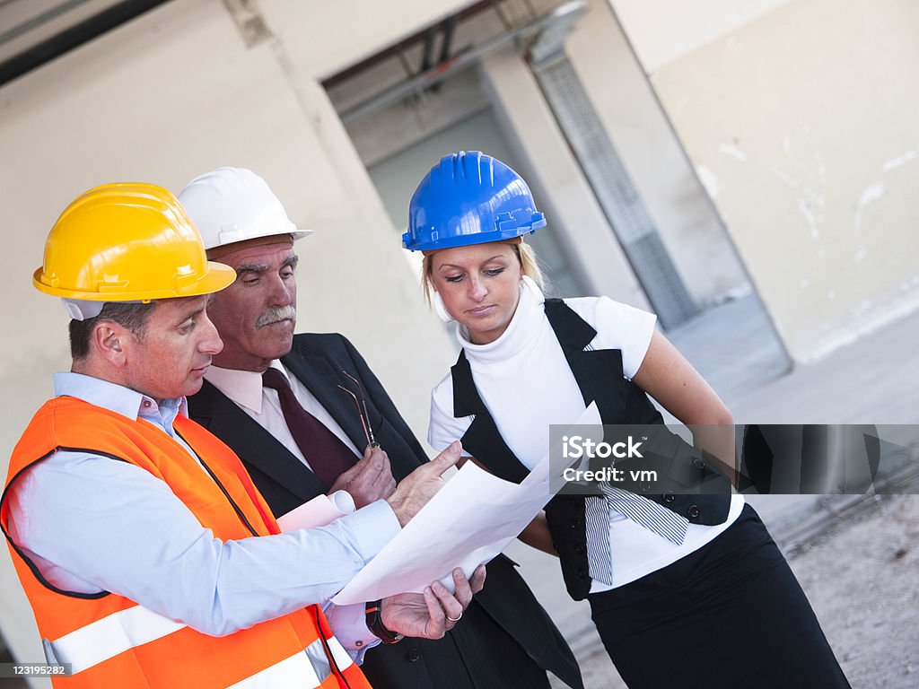 Groupe d'hommes d'affaires examinant un plan ensemble sur un Site de Construction - Photo de Adulte libre de droits
