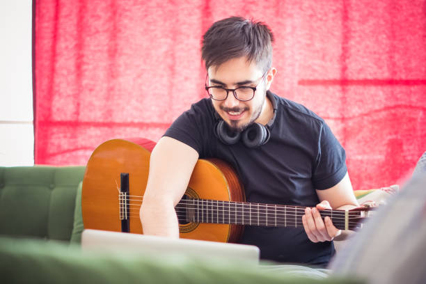 istock Young Man playing Guitar, taking online music lessons. 1231970617