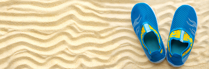 Banner 3:1. Water shoes on sandy beach. Top view. Copy space