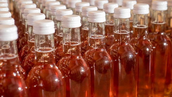 Fresh filled rose wine bottles with white seal screw caps waiting on a pallet for final labeling and packaging.