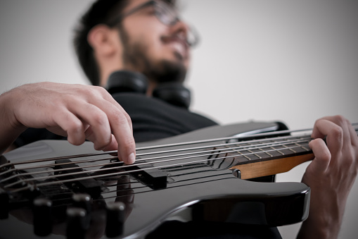 Concert view of musician, electric bass guitar player with during band performing rock music,  bassist player on stage