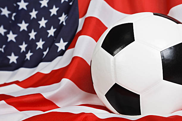 extreme close up of pelota de fútbol en cubrir bandera estadounidense - american football football focus on foreground team sport fotografías e imágenes de stock