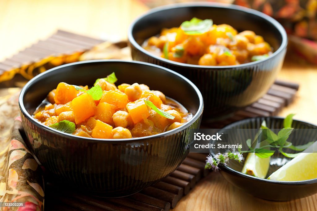 Three black bowls filled with pumpkin curry and side dishes Pumpkin curry with chick-peas Curry - Meal Stock Photo