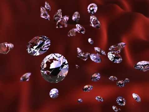 Diamonds scattered on red, fabric background. Precious stones in different sizes.