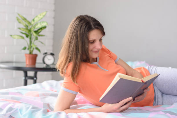 istock Girl at home lying in bed reads a book. 1232032410