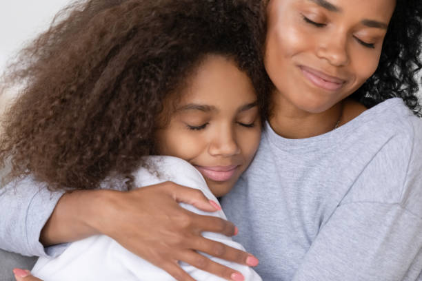 cuidar mãe solteira afro-americana abraçando filha adolescente, conceito de maternidade - adoption early teens teenager family - fotografias e filmes do acervo