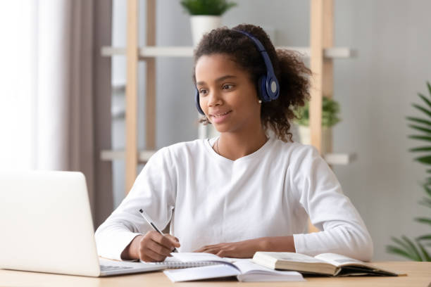 fille africaine utilisant l’étude d’écouteur avec l’enseignant de skype sur l’ordinateur portatif - high school student student computer laptop photos et images de collection