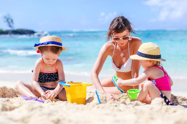 istock Mother and little daughters making sand castle at tropical beach 1232143983