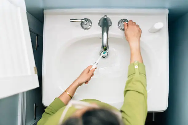 Woman brushing teeth in domestic bathroom