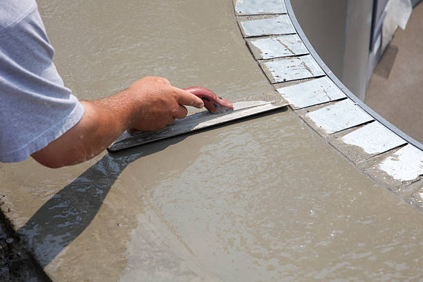 Man smoothing over wet cement in swimming pool construction