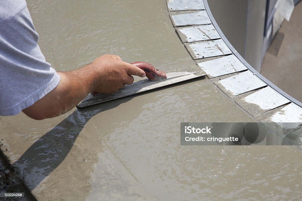 Man smoothing over wet cement in swimming pool construction hand troweling fresh concrete for a new custom pool deck Swimming Pool Stock Photo