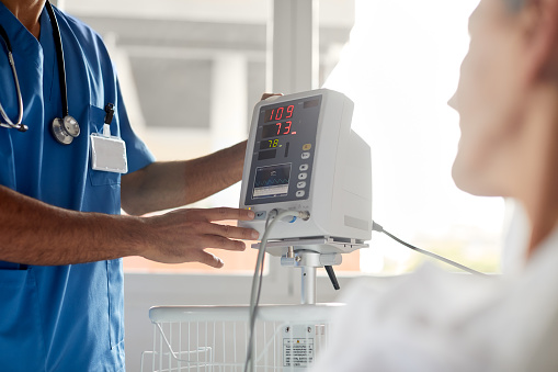 Asian Chinese doctor and nurse conducting electrocardiogram exam on patient at hospital