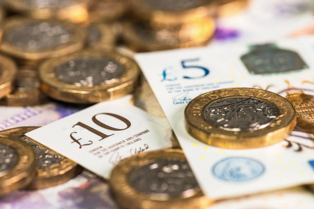 Close up of new UK currency Recently issued British polymer ten and five pound notes, with pound coins. one pound coin stock pictures, royalty-free photos & images