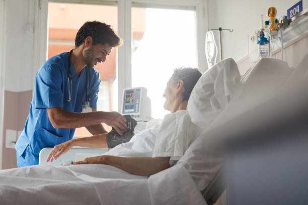 uma enfermeira está tomando o pulso de uma paciente do sexo feminino. - hospital patient bed nurse - fotografias e filmes do acervo