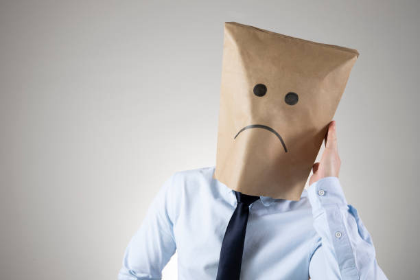 Businessman Wears Sad Face Paper Bag Businessman wears a paper bag with a sad face on it The economy has pushed his business down. anonymous businessman with paper bag on his head stock pictures, royalty-free photos & images