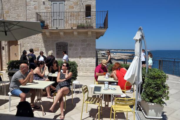 People sit in a cafe in Polignano a Mare Old Town in Apulia, Italy. With 50.7 million annual visitors Italy is one of the most visited countries.