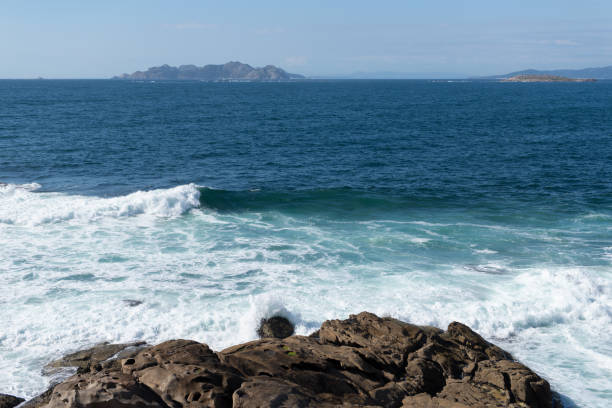 istock ocean wave splash on rocks on the coast on a sunny day with blue sky 1232414474