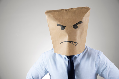 Businessman is wearing angry frowning paper bag mask