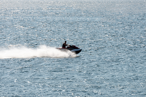 man riding a jet ski shooting in backlit by sunset