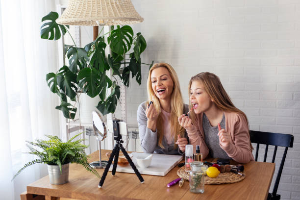 istock Mother and her daughter puting liquid lipstick on lips and record video about cosmetics on mobile phone 1232485220