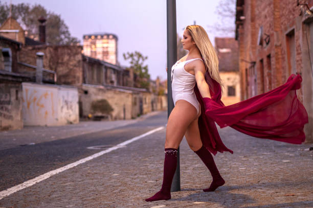 istock Blonde young pretty girl dancer perform in empty street leaning on pole 1232485580