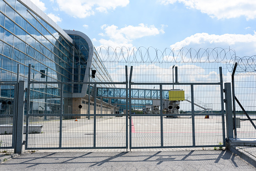 Airport fence grille on the background of passenger bridges for boarding passengers. Place for the test on the plate.