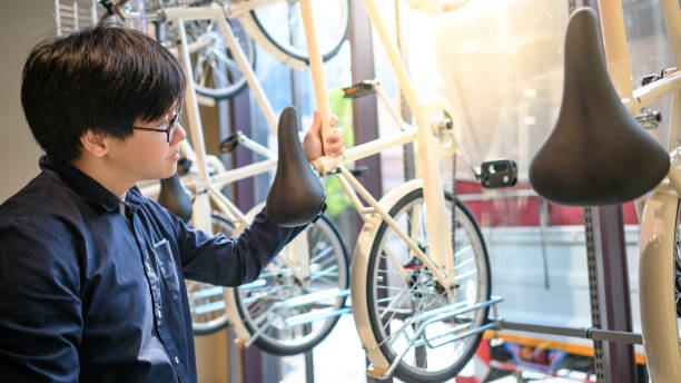 asiatischer mann kauft fahrrad im fahrradladen - fahrradrahmen stock-fotos und bilder