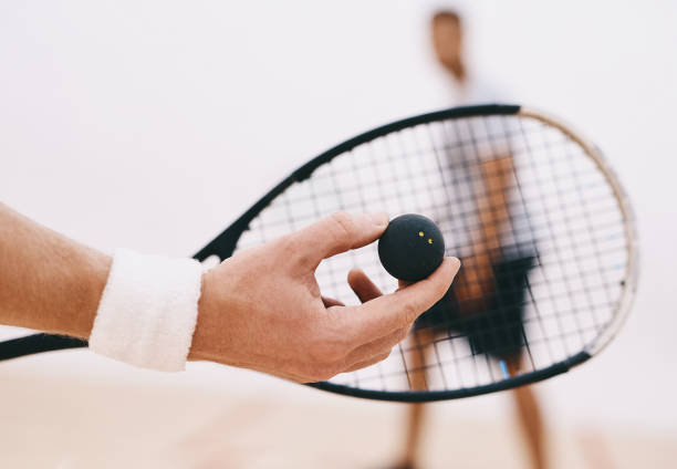 crossed squash rackets and ball on the wooden floor. Racquetball equipment on the court near red line. Photo with selective focus