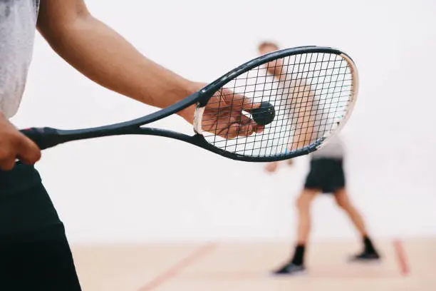 Cropped shot of a man serving a ball with a racket during a game of squash