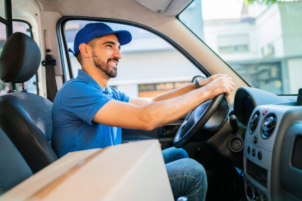 istock Delivery man driving van with cardboard boxes on seat. 1232542494