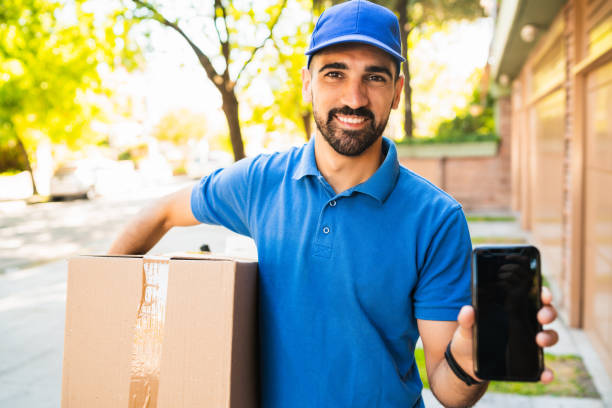 istock Delivery man holding package and showing smartphone. 1232542656