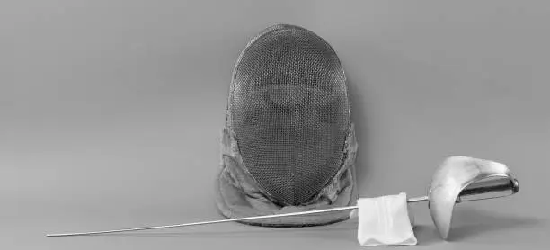fencing helmet and fencing rapier isolated on gray background