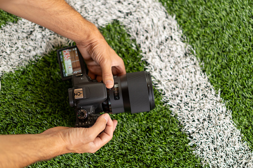 detail sports photographer shooting soccer with typlical white lines in grass top perspective